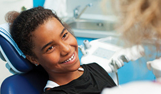 A smiling child sitting through a dental examination.